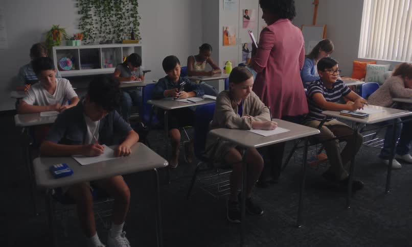 A classroom of students works on an assignment as the teacher observes