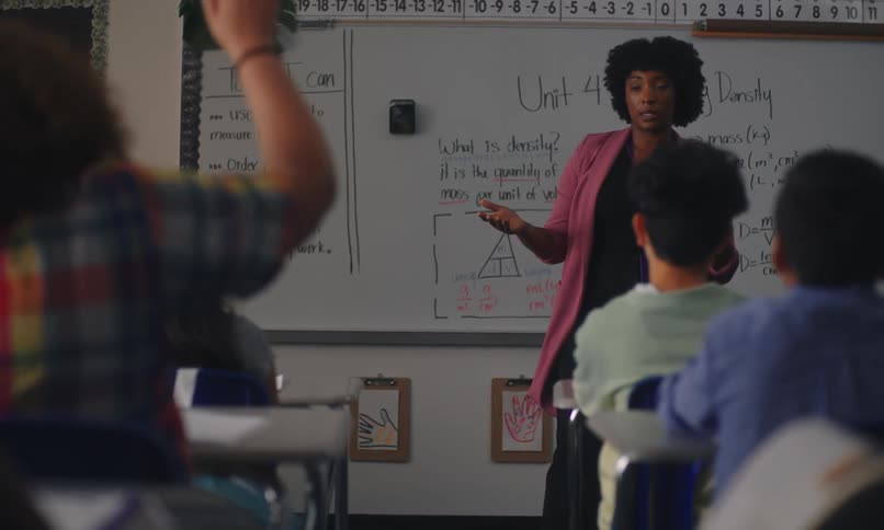A classroom setting with a teacher explaining how to measure length order objects by height and describe mass with a focus on calculating density