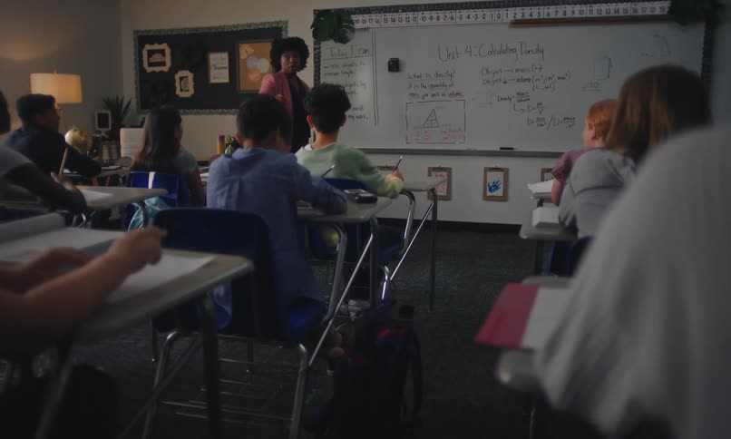 Teacher standing teaching in a classroom and students paying attention