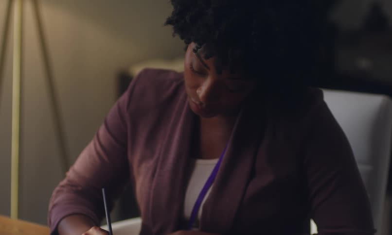 Close up of a woman taking notes on a notebook at home