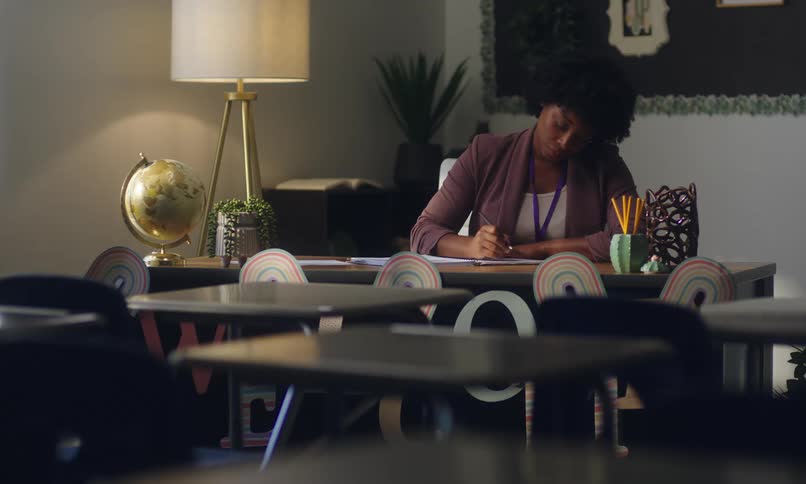 A female teacher works at a desk in a classroom