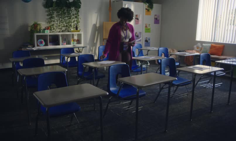 Teacher in classroom placing papers on students desks