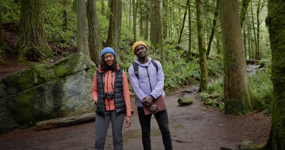 Smiling man and woman with a professional camera and a briefcase in the middle of a forest