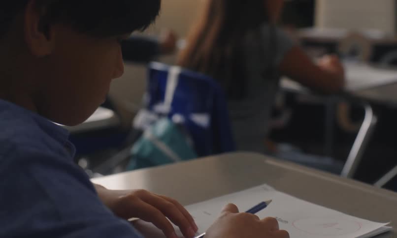 Teacher placing a test on a students desk in the classroom