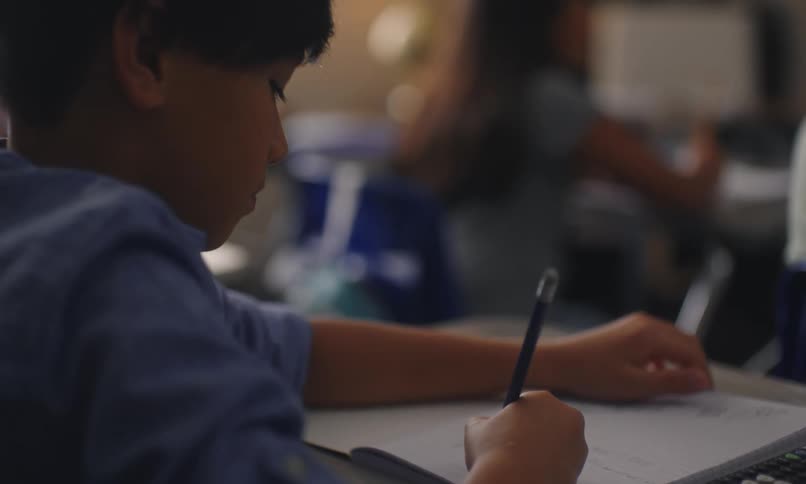 A young boy is working on math homework with a pencil and calculator