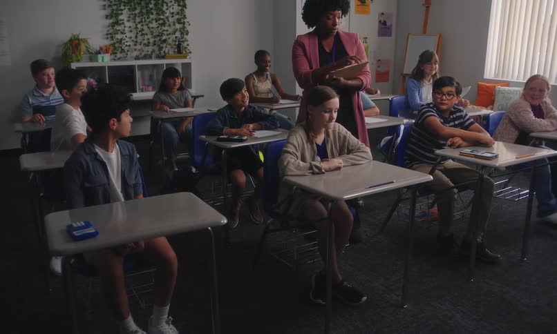 A teacher passes out an assignment to a classroom full of students