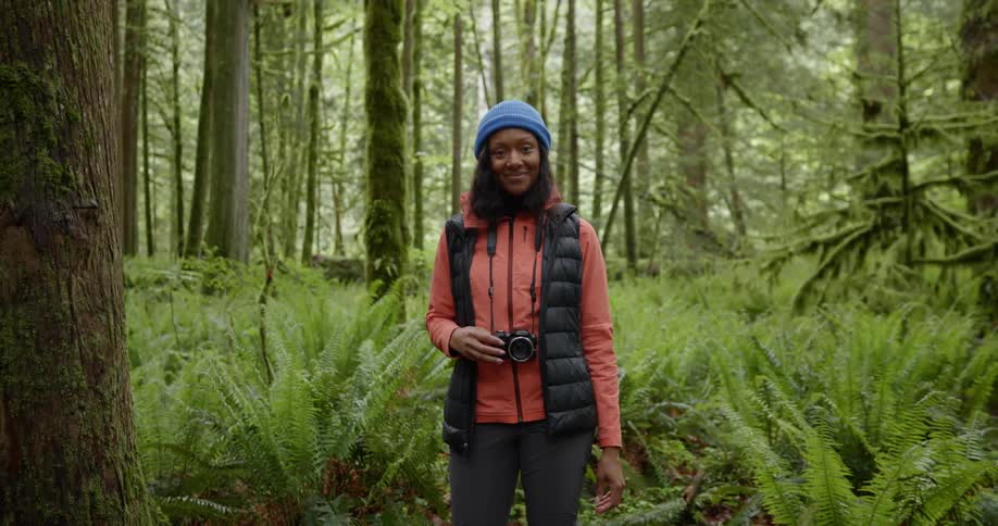 A woman holding a camera in the forest
