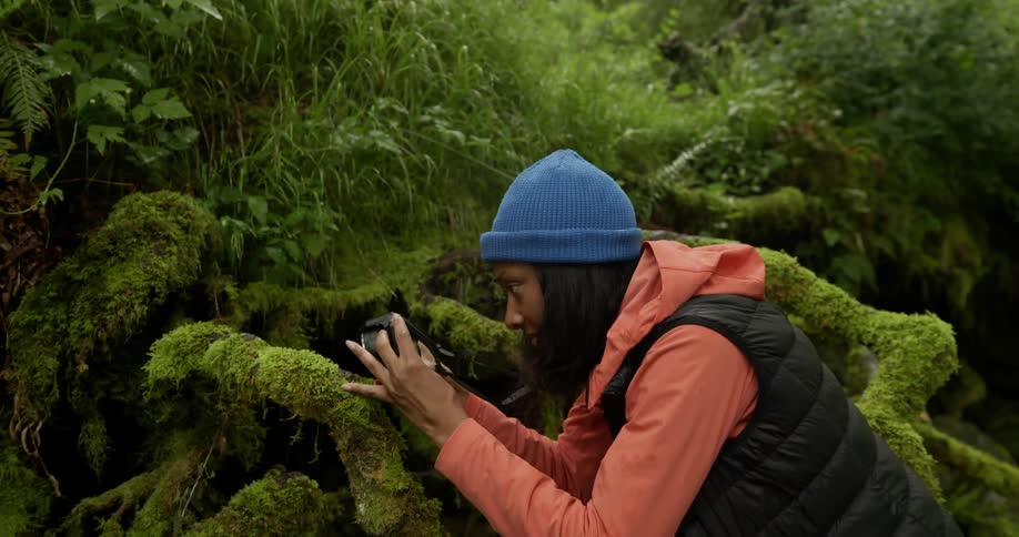 Female photographer in a natural environment with mosses using her professional camera
