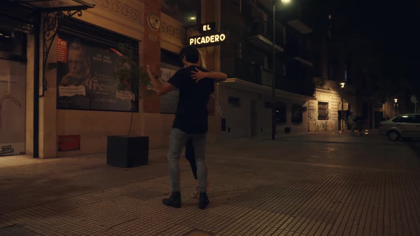 A couple dancing tango on the city streets at night
