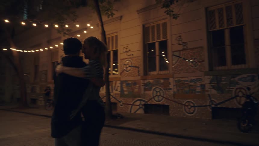 A couple dance romantically on an empty city street at night