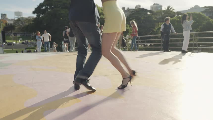 Man and woman in a public space dancing tango with people around