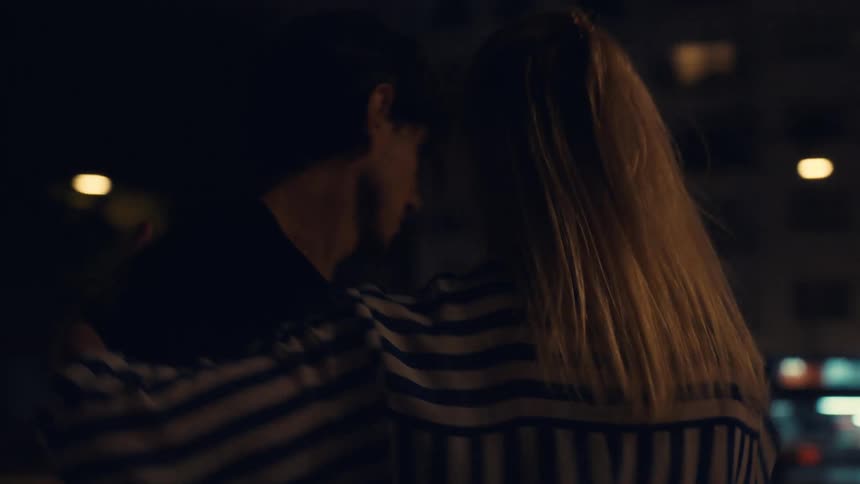 Man and woman dancing next to a busy street at night