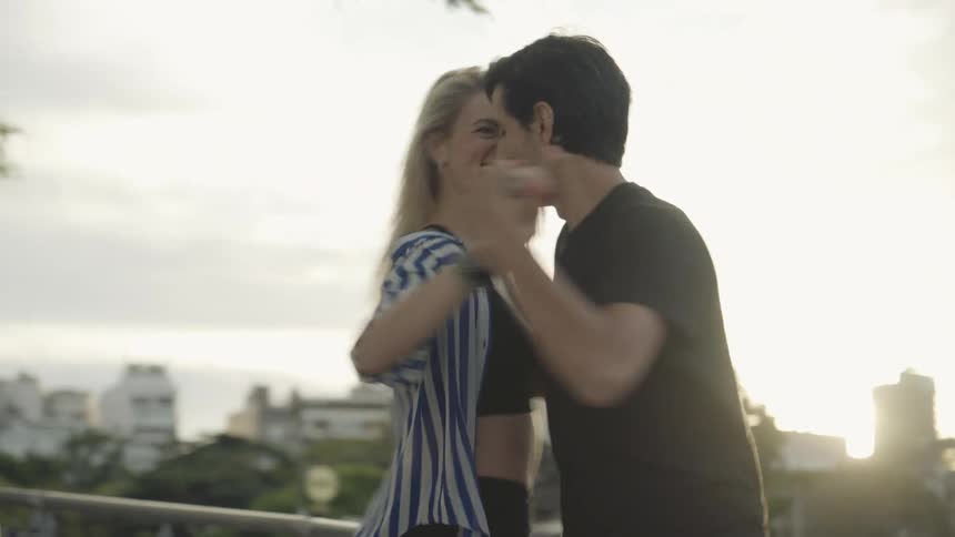 A man and a woman break into a romantic dance while strolling outdoors