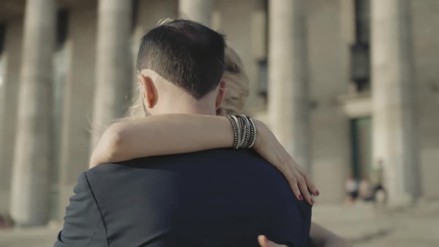 A man and a woman embrace and they spin in an artistic tone
