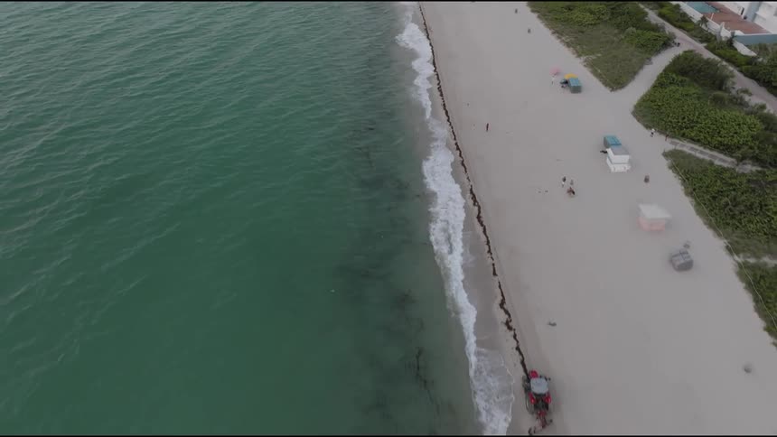 A camera pans over a beach as the waves crash on the shore