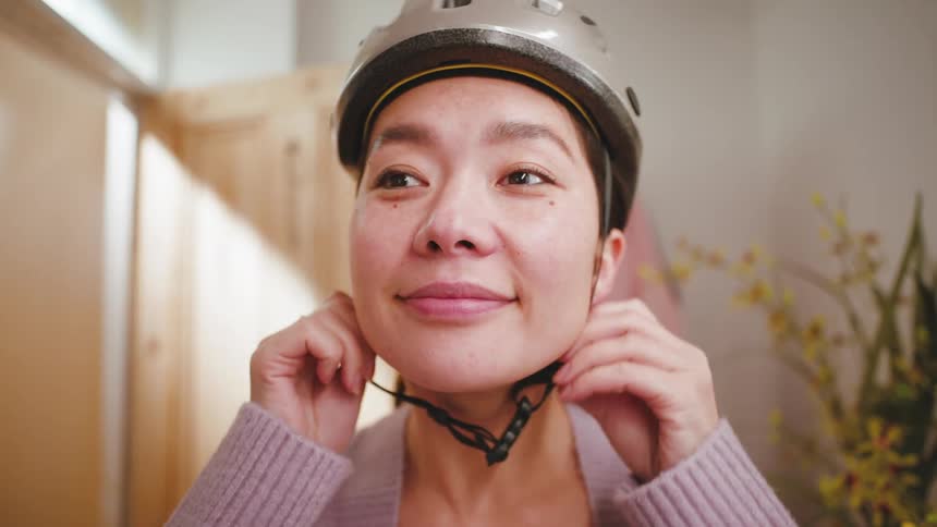 Close up of the face of a woman wearing a bicycle helmet indoors