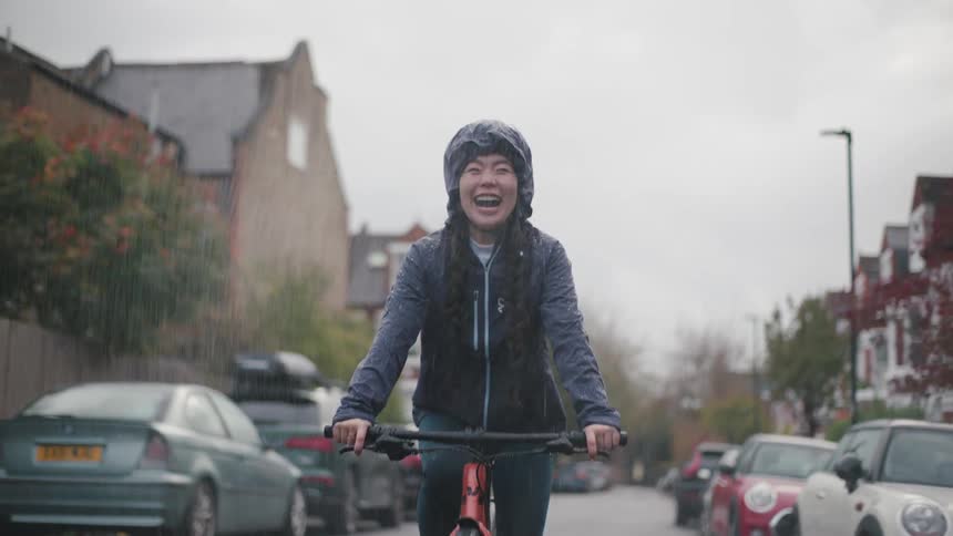 A woman riding a bicycle on a wet street during a rainstorm