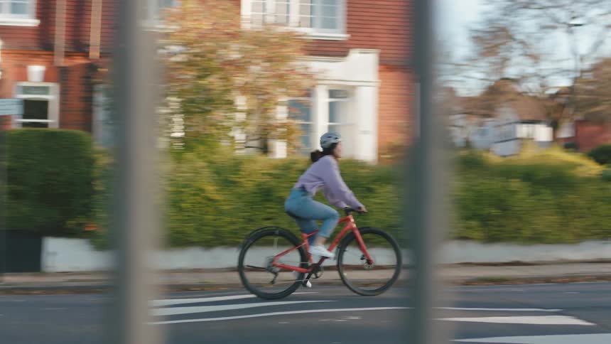 Female cyclist rides over a speed bump while cycling through a residential neighborhood