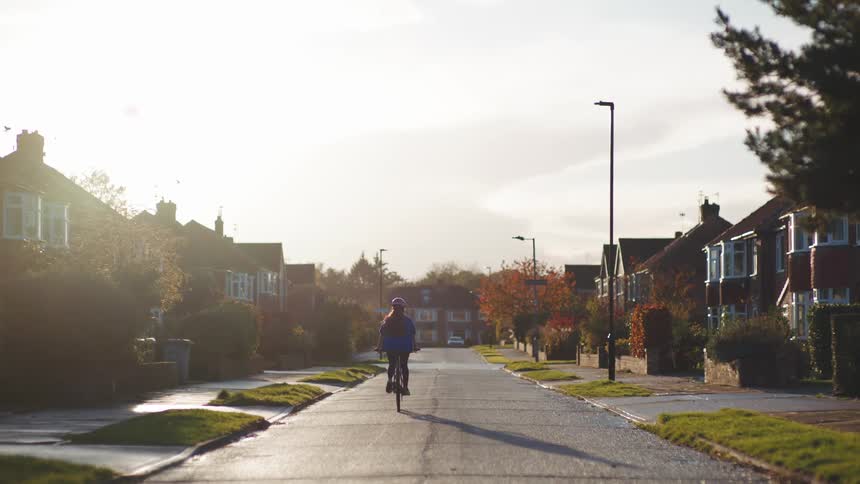 Woman riding a bicycle down a street in a residential neighborhood