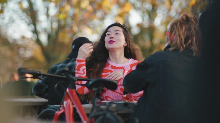 A group of people sitting outdoors at a park surrounded by autumn foliage
