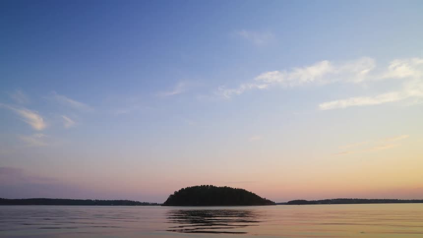 A serene lake reflecting the sky with a forested island at its center