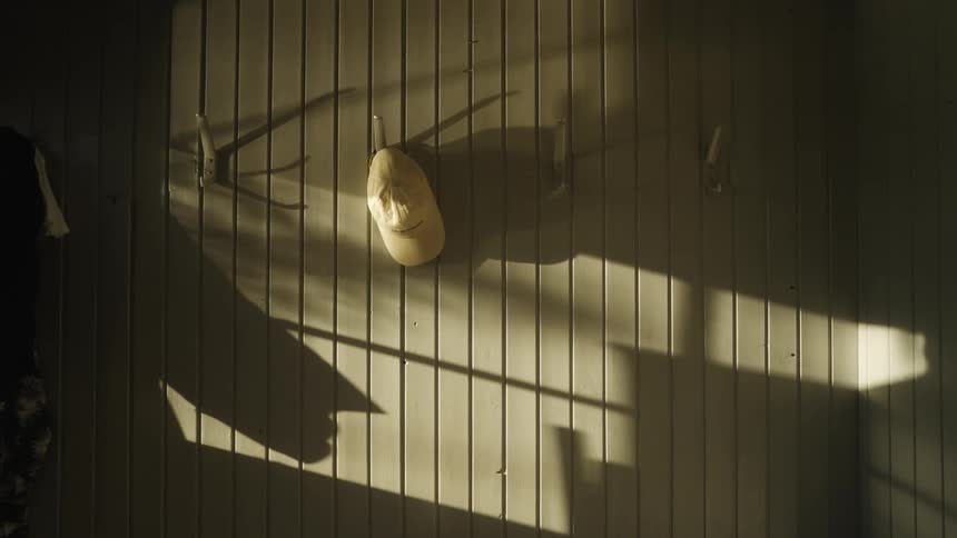Person throwing a white cap at the wall with a hanger