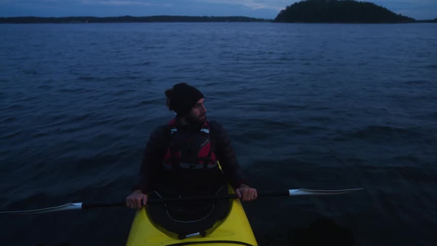 Man looking to the side as he sits quietly in a kayak on a calm ocean