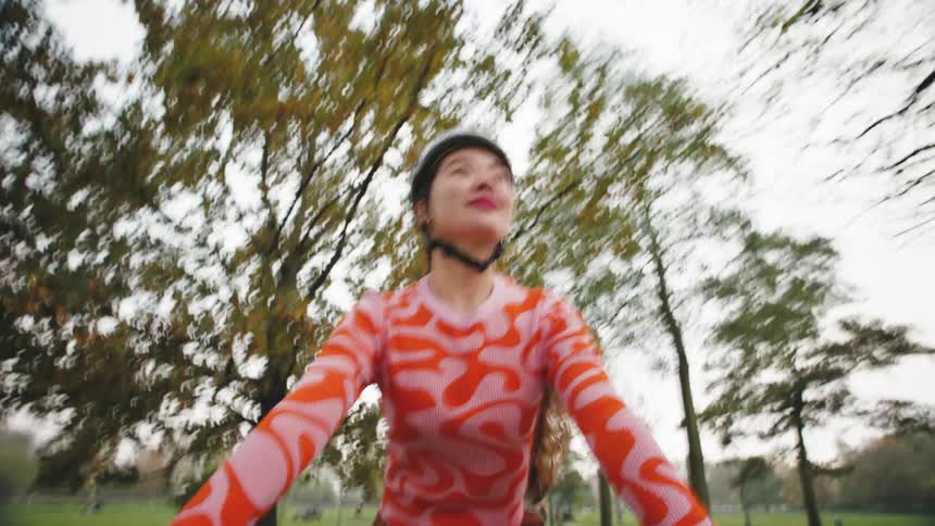 Woman with white helmet riding a bicycle in a park with trees