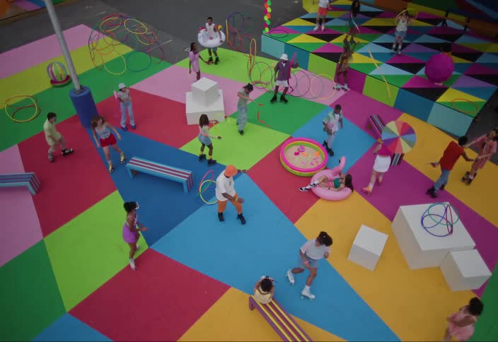 Happy people play and dance on a colorful outdoor playground with geometric patterns on the ground