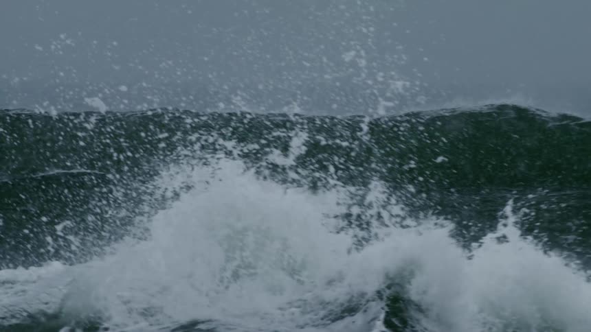 Crashing ocean waves creating a misty spray against a dark overcast sky