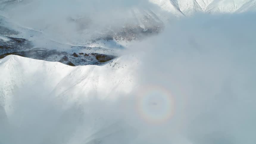 A snowy mountainous landscape partially obscured by clouds