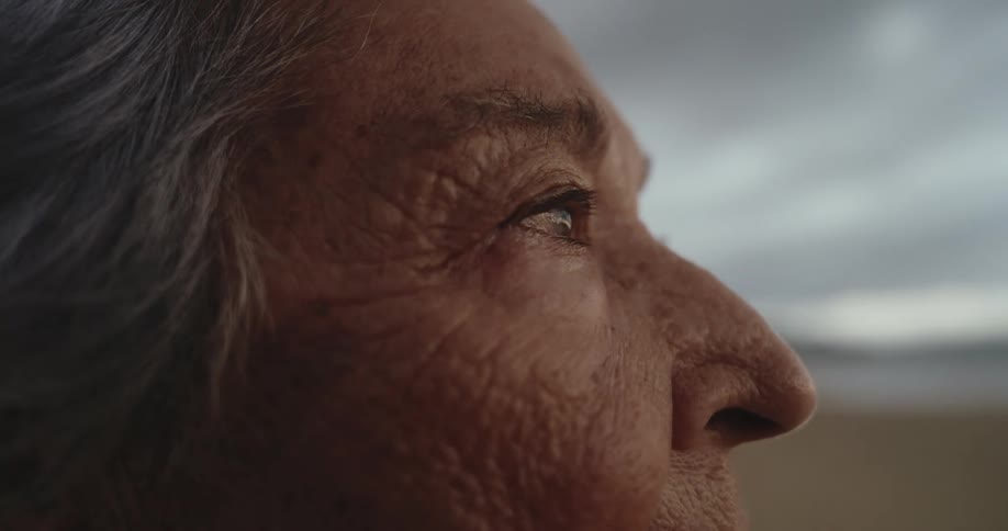 Side portrait of an elderly person blinking while standing on a beach
