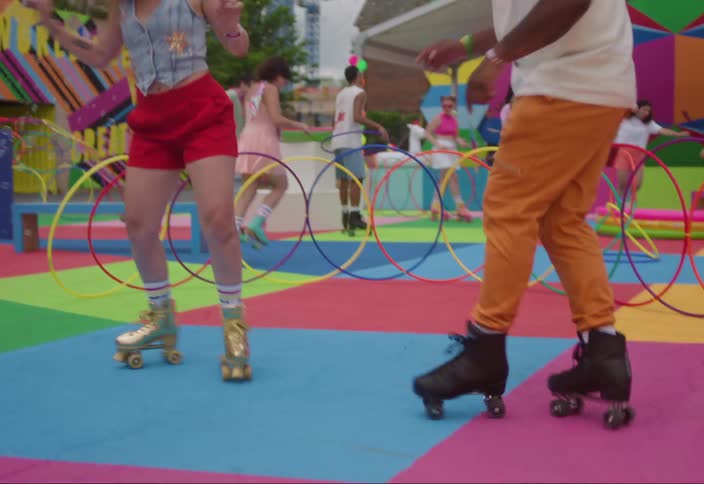 Group of people dancing with roller skates on a colorful playground with buildings of a metropolis in the background