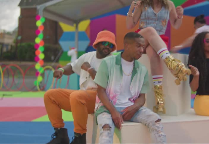 A group of friends sitting on colorful steps at an outdoor event dancing to the music