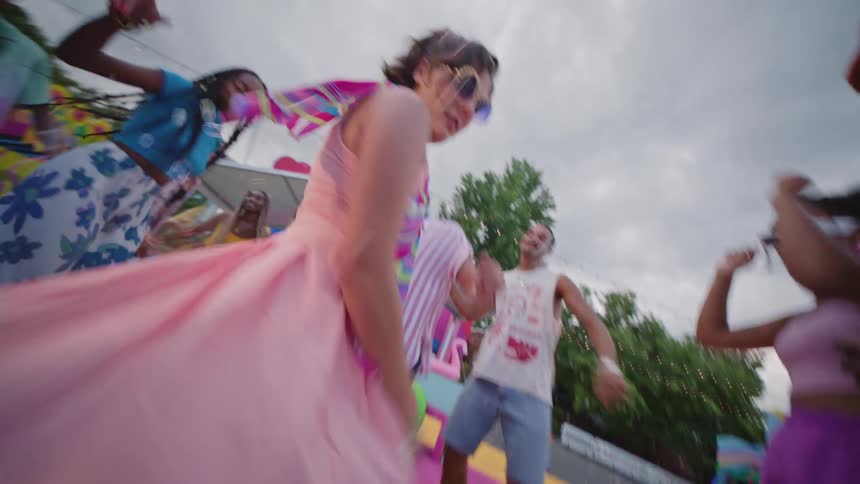 A group of people in colorful clothes using roller on a colorful floor and some of them are spinning
