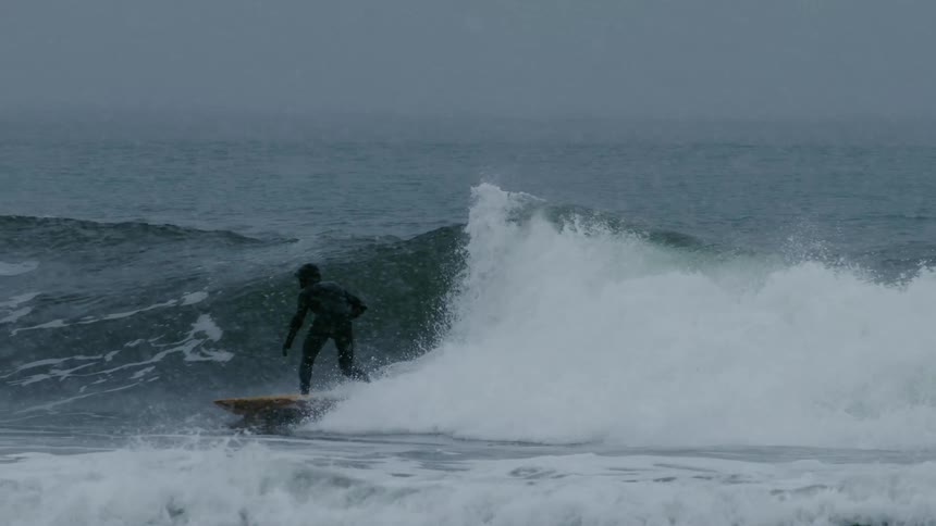 A surfer riding a wave on a yellow surfboard riding a ocean wave