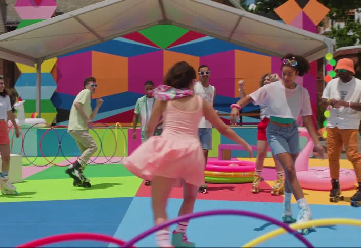 A group of people roller skating in an outdoor rink with colorful flooring