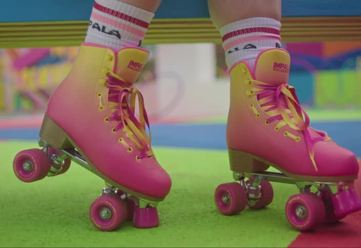 Legs of a woman with pink roller skates on a playground