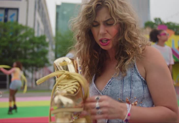 Blonde woman sitting showing her golden skates to her friends