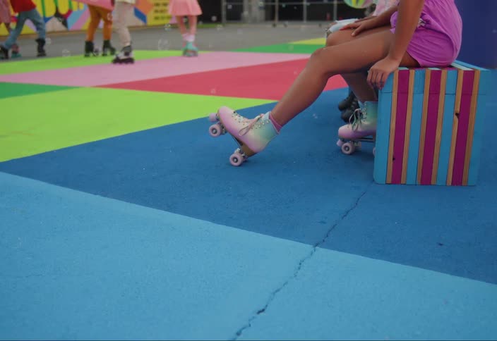 People sitting and rollerblading on a colorful playground and soap bubbles flying