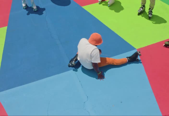 Man on roller skates on a wheel with other people doing a roller dance trick