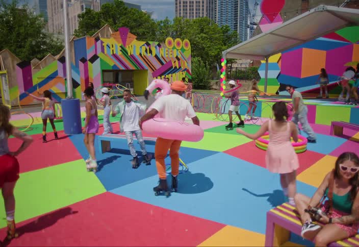 Group of people on a colorful playground rollerblading with buildings of a metropolis in the background