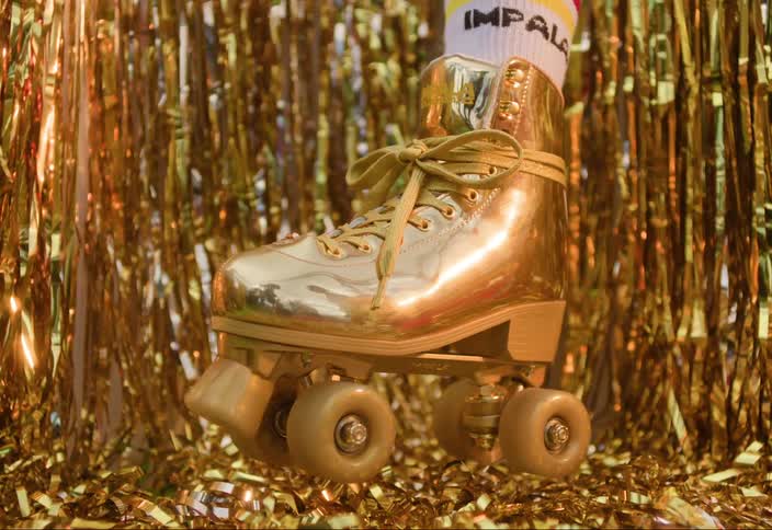A single goldcolored roller skate and laces against a backdrop of shiny gold tinsel