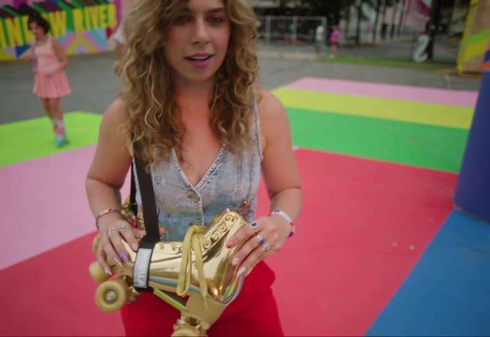 Woman walking on a playground carrying golden skates at her waist