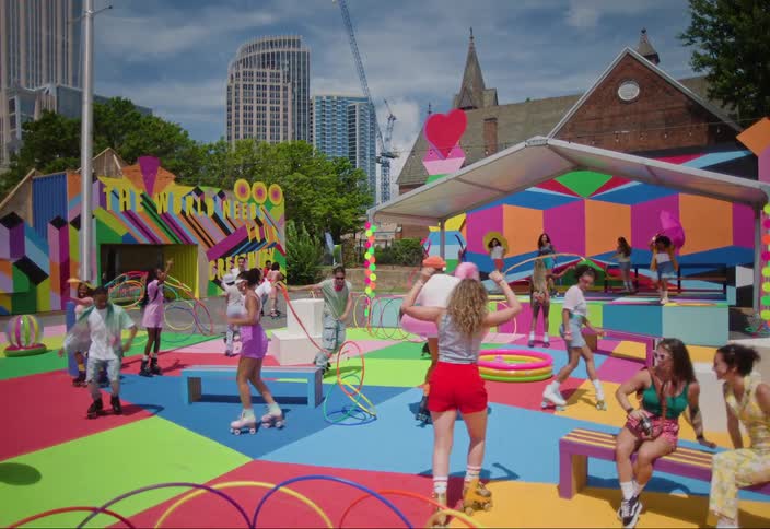 Colorful outdoor scene with several people skating on a vibrant and decorated skating rink