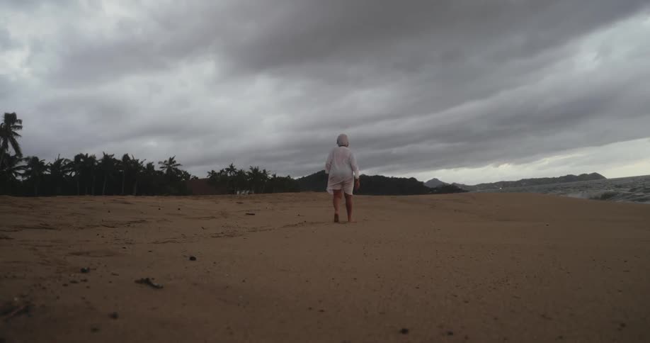 Elderly woman walking on the sand at the beach