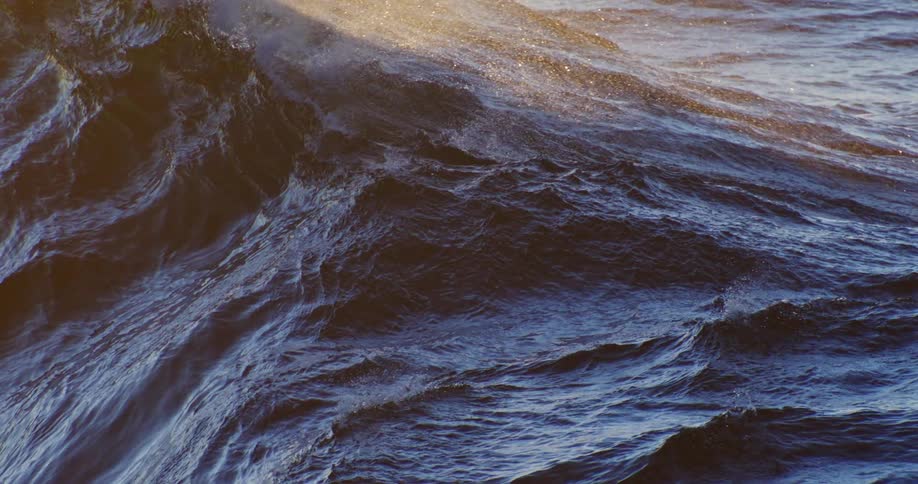 Dark blue ocean waves with sunlight reflecting off the crests