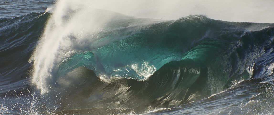 A large wave is crashing in the blue water