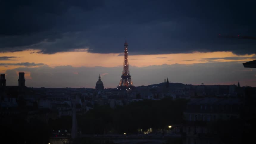 The eiffel tower is lit up with sparkling lights at dusk