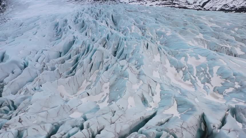 Jagged glacier borders snowy mountains on an arctic day